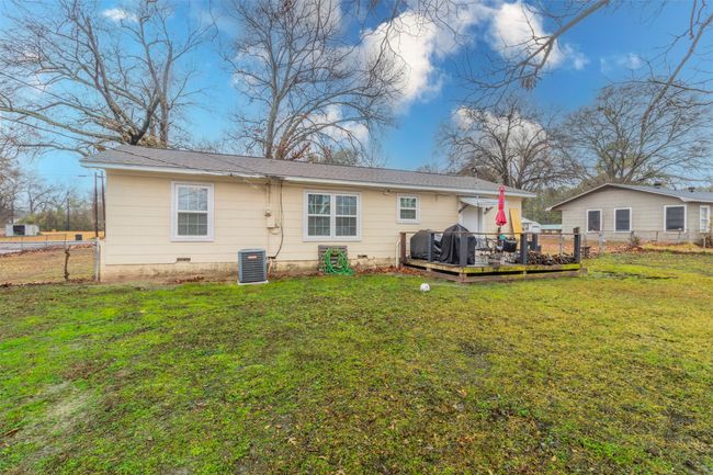 Back of house with fence, a wooden deck, central AC unit, a lawn, and crawl space | Image 17