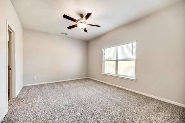 Carpeted empty room with baseboards, a ceiling fan, and visible vents | Image 8