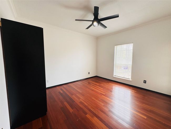 Bedroom 1 with wood finished floors, ceiling fan, baseboards, and ornamental molding | Image 5