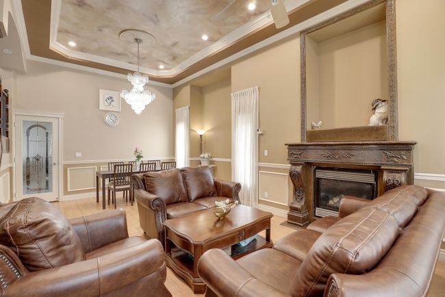 Living room with a chandelier, a raised ceiling, crown molding, and a decorative wall | Image 9