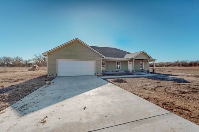 Ranch-style house featuring concrete driveway, roof with shingles, an attached garage, and covered porch | Image 5