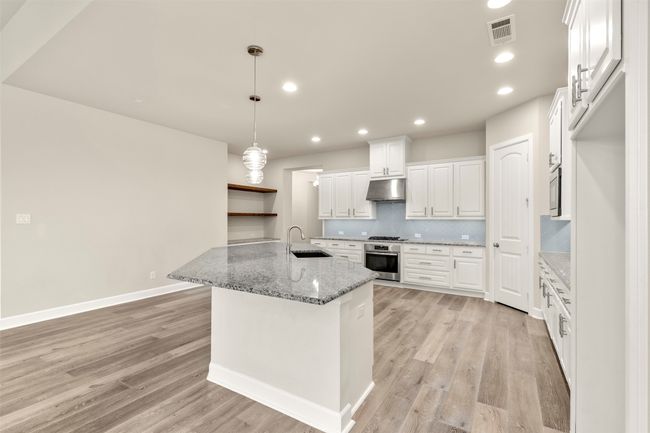 Kitchen featuring under cabinet range hood, stainless steel appliances, a sink, light wood-type flooring, and recessed lighting | Image 7