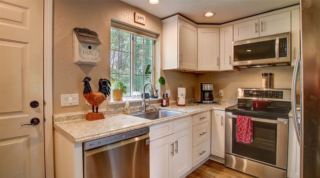 Kitchen with appliances with stainless steel finishes, white cabinets, wood finished floors, recessed lighting, and a textured wall | Image 13