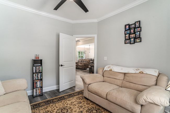 Living area with a ceiling fan, crown molding, wood finished floors, and baseboards | Image 6