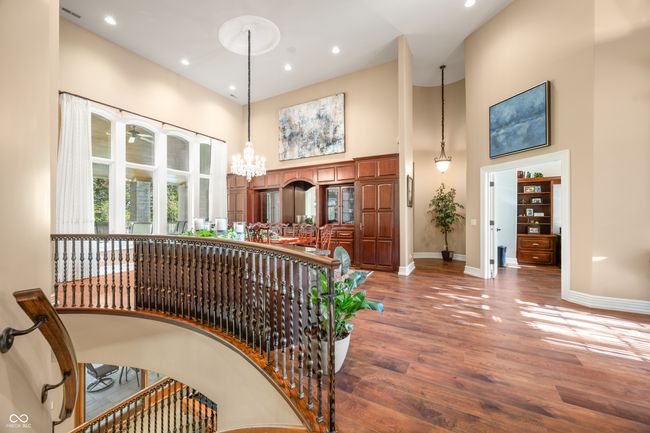 staircase featuring an inviting chandelier, wood finished floors, baseboards, and a high ceiling | Image 15