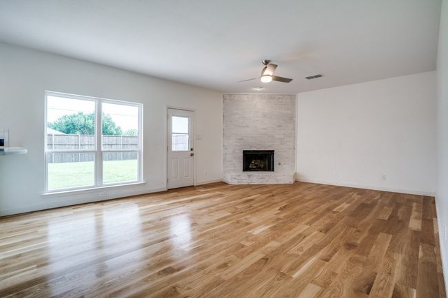 Unfurnished living room with ceiling fan, light wood-style flooring, a large fireplace, and baseboards | Image 6
