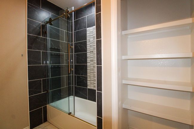Bathroom featuring bath / shower combo with glass door and marble finish flooring | Image 12