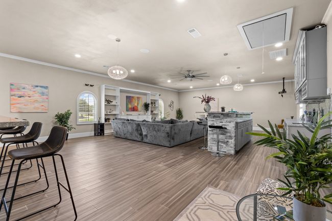 Living area with attic access, crown molding, wood finished floors, a ceiling fan, and recessed lighting | Image 24