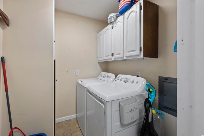 Washroom with cabinet space, washer and dryer, and baseboards | Image 21
