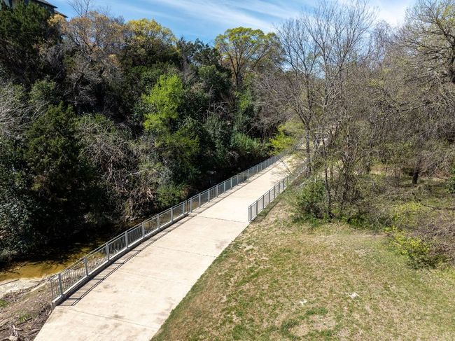 View of home's community with a wooded view, fence, and a lawn | Image 27