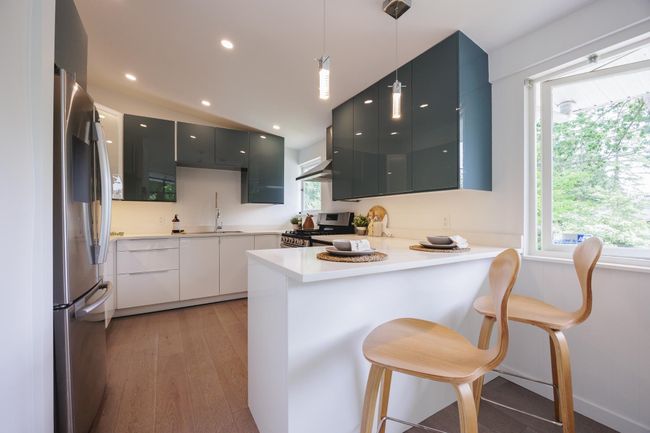 Kitchen with stainless steel appliances, a peninsula, modern cabinets, light wood-style floors, and decorative light fixtures | Image 5