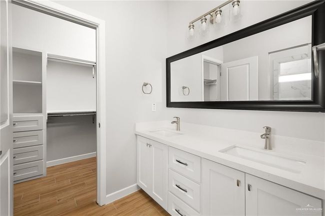 Full bathroom with a spacious closet, double vanity, a sink, and wood finished floors | Image 9
