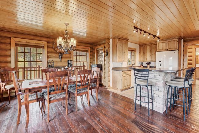 Dining area featuring wooden ceiling, log walls, a chandelier, dark wood-style flooring, and track lighting | Image 9