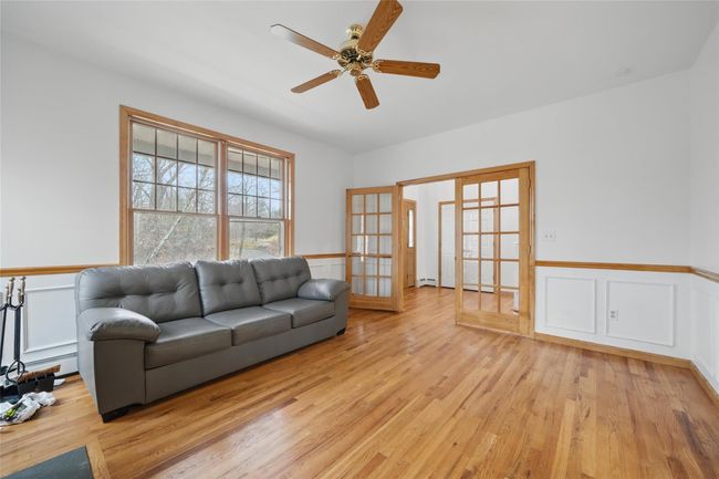 Living room featuring light wood finished floors, a ceiling fan, a wainscoted wall, and french doors | Image 22