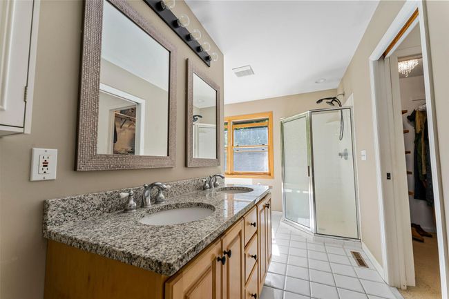 The luxurious en suite bathroom feels like a private spa, featuring a beautifully tiled walk-in shower, a roomy jetted tub for soaking, and a double vanity. | Image 14