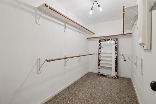 Spacious walk-in closet with wooden rods, carpeted floor, and ample storage. | Image 19