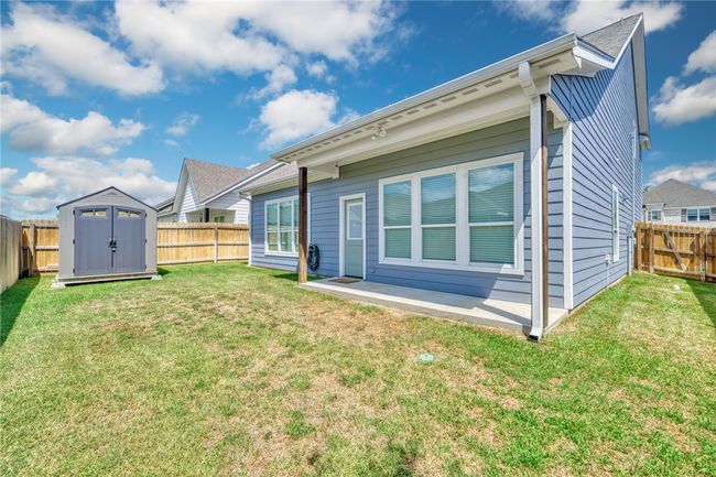 Back of property with a fenced backyard, a storage shed, and a patio | Image 32