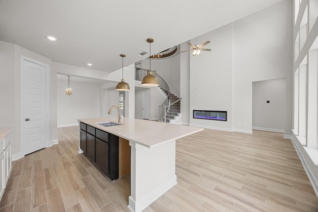 Kitchen with a sink, light wood-type flooring, light countertops, baseboards, and a center island with sink | Image 10