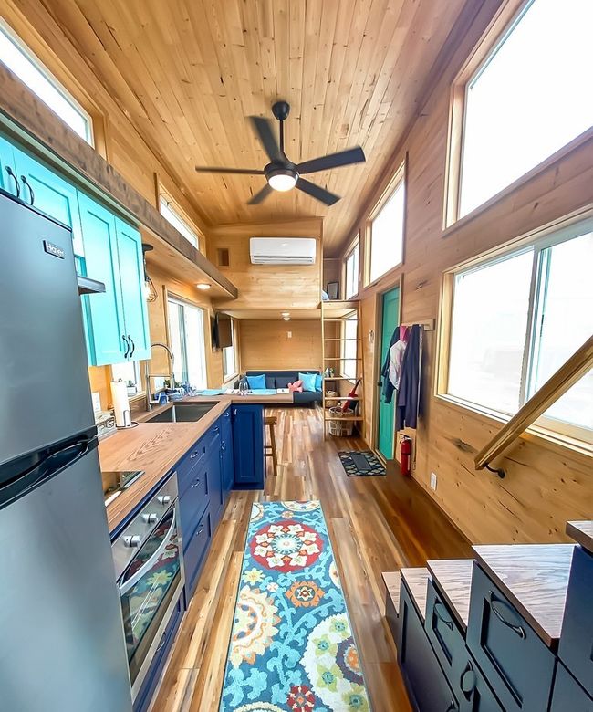 Kitchen featuring stainless steel appliances, blue cabinets, butcher block countertops, an AC wall unit, and wooden walls | Image 32