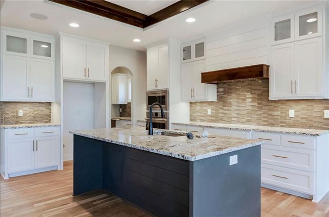 Kitchen with appliances with stainless steel finishes, tasteful backsplash, light wood-style floors, recessed lighting, and an island with sink | Image 8