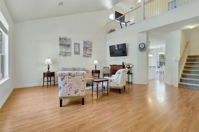 Living room featuring stairway, wood finished floors, and a towering ceiling | Image 6
