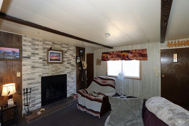 Living room with wood walls, beamed ceiling, a brick fireplace, and carpet flooring | Image 12