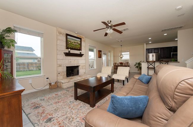 Living area with a ceiling fan, baseboards, a stone fireplace, recessed lighting, and tile patterned floors | Image 12