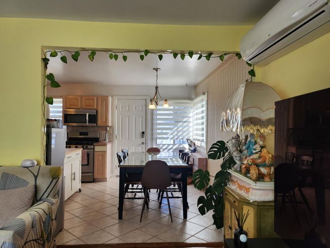 Dining area with a wall mounted air conditioner, a chandelier, and light tile patterned flooring | Image 7