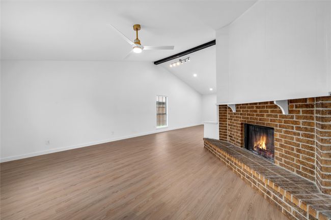 Unfurnished living room featuring wood finished floors, a brick fireplace, ceiling fan, and baseboards | Image 10