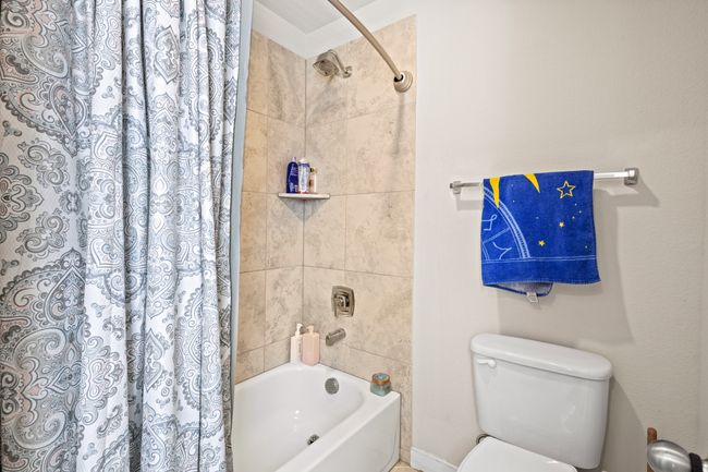 Full bathroom featuring toilet and shower / tub combo with curtain | Image 25