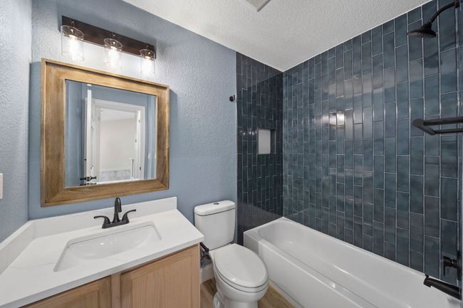 Full bathroom featuring vanity, tub / shower combination, a textured wall, and a textured ceiling | Image 18