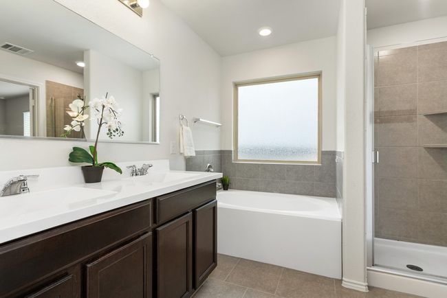 The primary bathroom features dual vanities, a soaking tub, a walk-in shower, walk-in closet, and rain glass for privacy while offering natural light! | Image 15