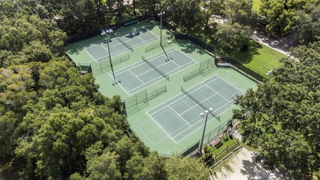 This aerial shot highlights the public tennis courts in Windermere, beautifully nestled among mature oak trees for a peaceful and shaded atmosphere. These well-maintained courts provide residents and visitors alike with a recreational space to stay active and enjoy the outdoors. Surrounded by lush greenery and set in one of Central Florida’s most charming towns, they’re a perfect example of how Windermere blends community amenities with natural beauty. Whether you're a casual player or a competitive enthusiast, these courts offer a welcoming and scenic spot to serve up a match. | Image 38