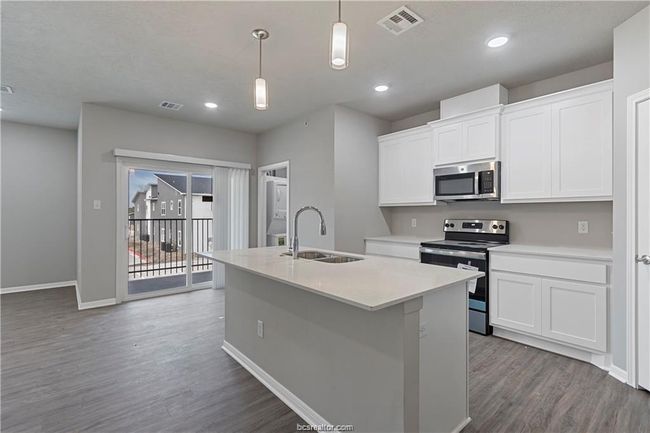 Kitchen with pendant lighting, a center island with sink, white cabinets, appliances with stainless steel finishes, and sink | Image 7