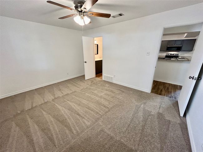 Unfurnished bedroom featuring light colored carpet, baseboards, connected bathroom, and a ceiling fan | Image 14