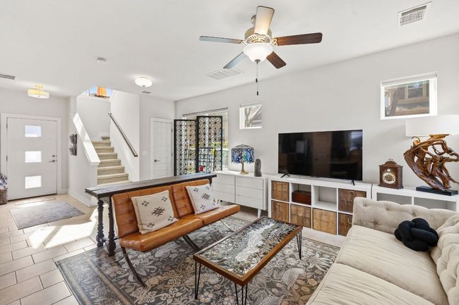 Tiled living room featuring stairs, ceiling fan, and visible vents | Image 5