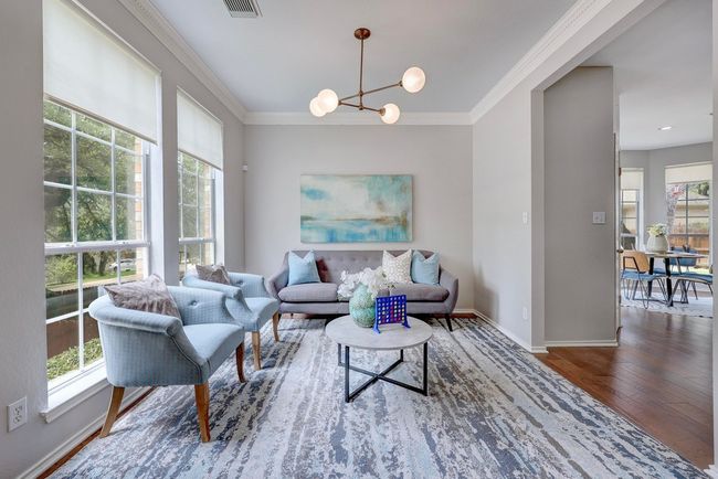 Living area featuring plenty of natural light, wood finished floors, a chandelier, crown molding, and baseboards | Image 7