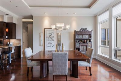 A sophisticated dining room with mountain views, highlighted by large windows, an elegant pendant light fixture and warm natural lighting. | Image 3