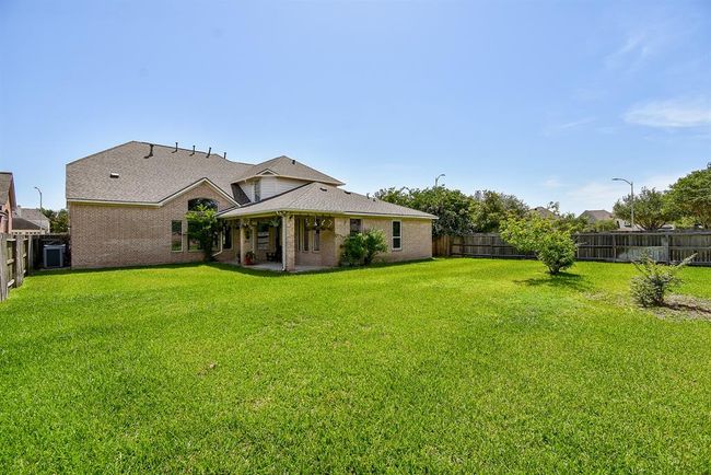 A covered patio at the rear of the home offers the ideal spot for shaded relaxation or outdoor dining, overlooking the backyard and perfectly blending indoor-outdoor living. | Image 29