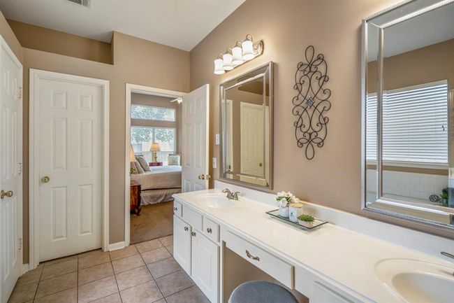 Looking back towards the bedroom from inside the bath, this view highlights the double vanities with decorative mirrors. On the left side of the bathroom, two doorways are visible—one leads to the walk-in closet, and the other to the water closet, enhancing the bathroom's functionality and layout. | Image 21