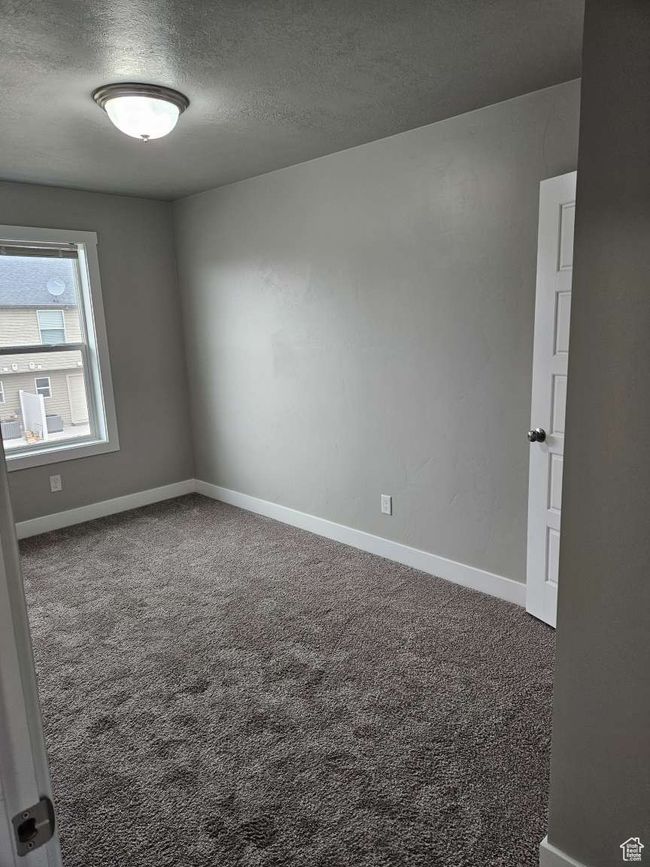 Empty room with a textured ceiling, baseboards, and carpet floors | Image 12