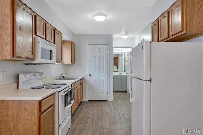 Kitchen with sink, white appliances, LVP flooring, and a textured ceiling | Image 5