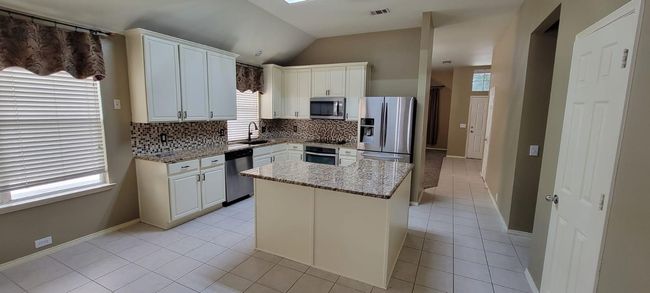 Kitchen featuring decorative backsplash, plenty of natural light, appliances with stainless steel finishes, light tile patterned floors, and lofted ceiling | Image 8