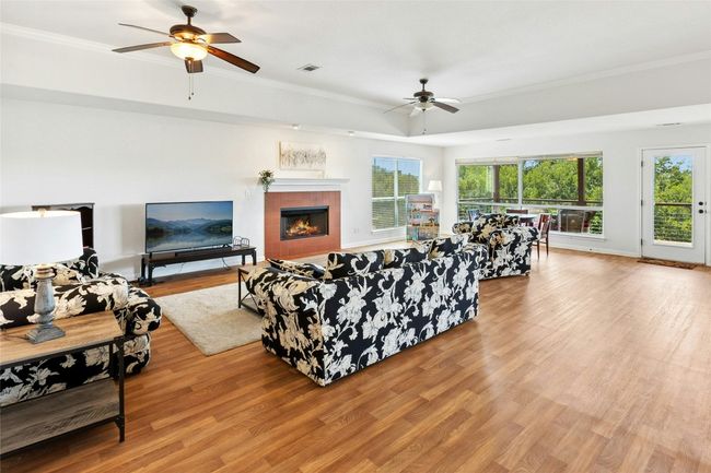 Living room featuring a ceiling fan, crown molding, a tile fireplace, and wood finished floors | Image 15