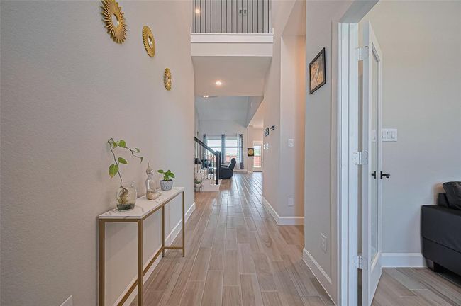 Welcoming entryway with high ceilings, wood-look tile flooring, and elegant wall accents creating a warm and inviting first impression. | Image 4