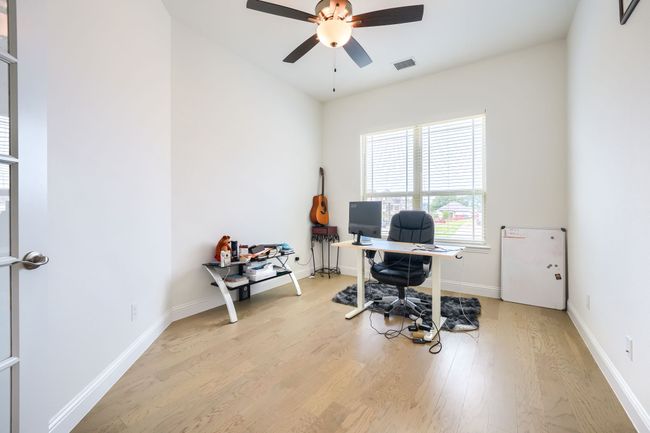 Home office featuring ceiling fan, baseboards, light wood finished floors, and visible vents | Image 15