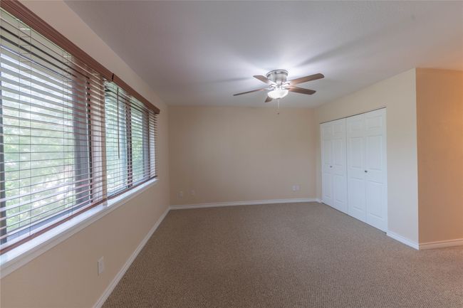 Unfurnished bedroom with carpet, baseboards, a closet, and ceiling fan | Image 18