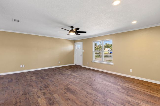Empty room featuring dark wood-style floors, crown molding, visible vents, and baseboards | Image 16