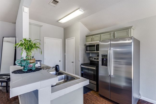 Kitchen featuring kitchen peninsula, dark hardwood / wood-style flooring, sink, and appliances with stainless steel finishes | Image 8
