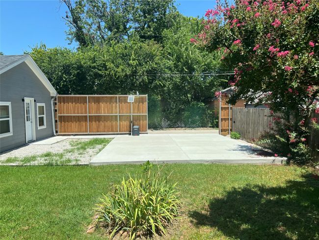 Great backyard with grassy area, large parking pad and nice electric gate. To the left is the separate guest house. | Image 29
